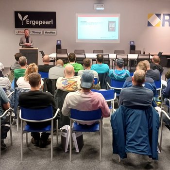 Kaminkehrer Vortrag in einem Seminarraum mit Zuhörern und Präsentation an der Wand