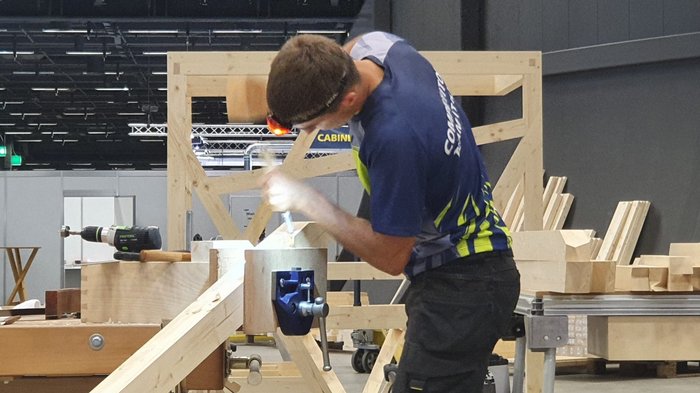 WorldSkills 2022 Special Edition: Zimmerer Marcel Bolego holt Silbermedaille Mann bearbeitet Holz mit Hammer und Meißel in Werkstatt