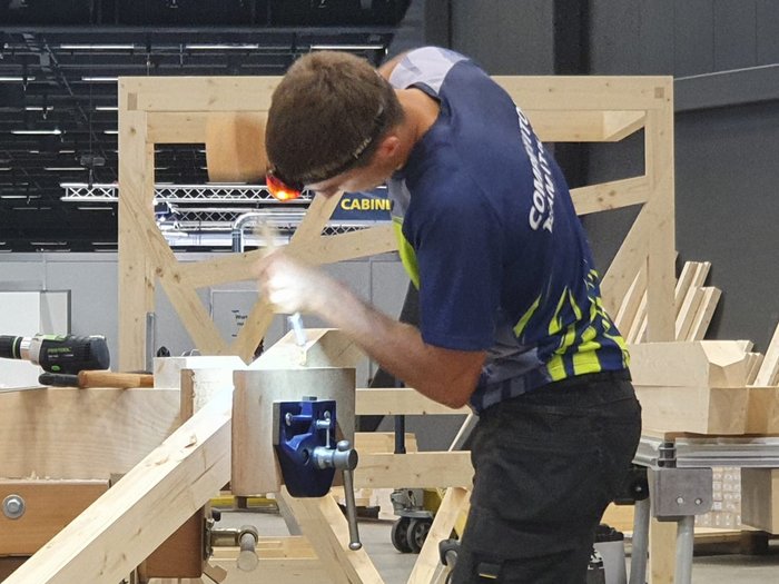 WorldSkills 2022 Special Edition: Zimmerer Marcel Bolego holt Silbermedaille Mann bearbeitet Holz mit Hammer und Meißel in Werkstatt