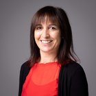 Waltraud Elisabeth Thaler Ritratto di donna sorridente con maglia rossa e cardigan nero su sfondo grigio