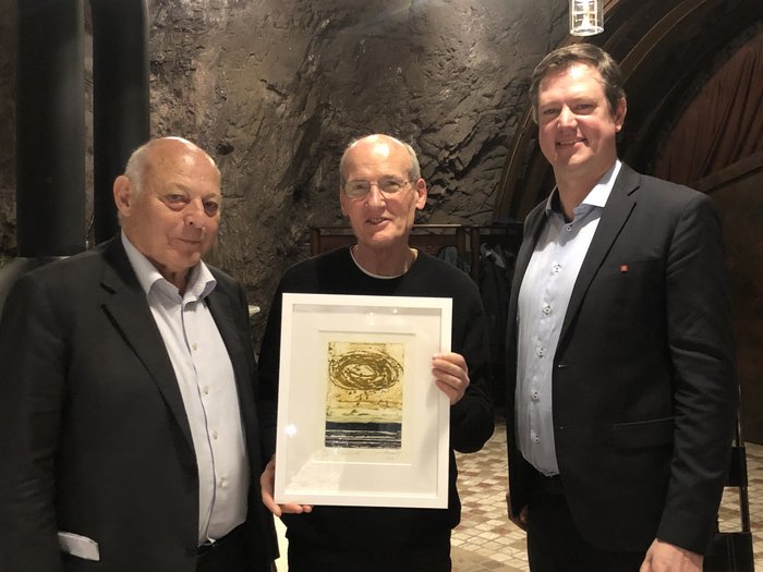 Ente Bilaterale: un doveroso riconoscimento ai protagonisti Tre uomini, uno tiene un'opera d'arte incorniciata, in una stanza di pietra