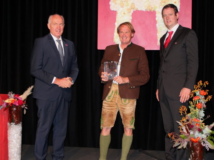 „Kinder, werdet Handwerker!“ Drei Männer bei einer Preisverleihung, einer in Trachten, zwei in Anzügen