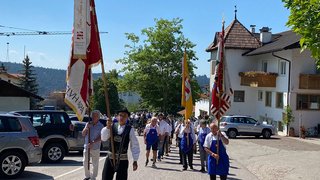 News Sfilata tradizionale con persone in costumi e bandiere sotto il sole