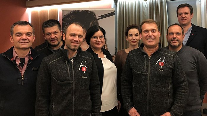 Kein Gemeinderat ohne Handwerk Gruppe von acht Personen steht in einem Raum vor einer Gardine und einem Plakat