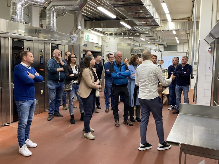 Riunione del circondario Bressanone di lvh.apa Gruppo ascolta una persona in una cucina industriale moderna