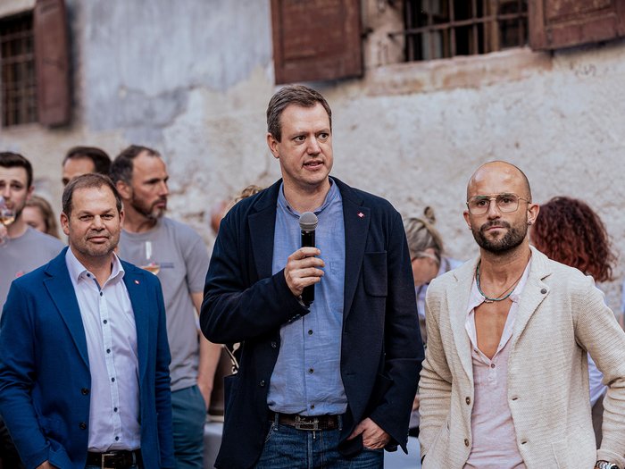 Generation-H Aperitif Drei Männer, einer spricht mit Mikrofon bei einer Veranstaltung im Freien