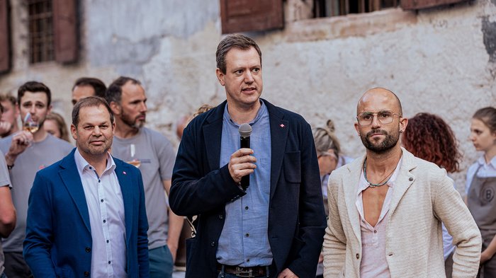 Generation-H Aperitif Drei Männer, einer spricht mit Mikrofon bei einer Veranstaltung im Freien