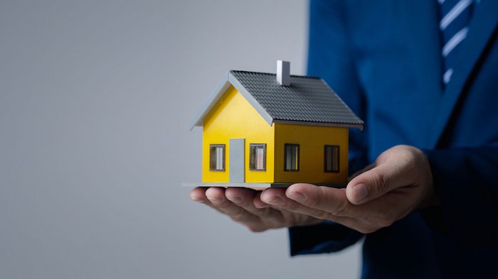 Edilizia: prime novità e semplificazioni sul fronte casa Persona che tiene una casa in miniatura in mano su sfondo neutro