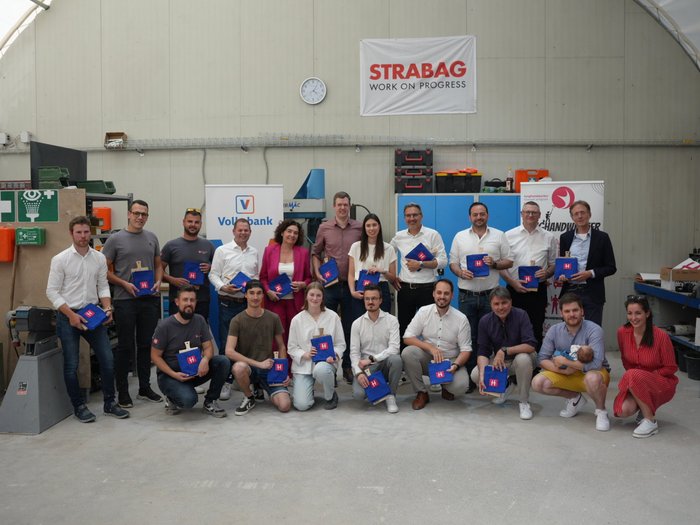 Premiati i giovani artigiani dell'anno Foto di gruppo di 19 persone con borse blu in un'officina