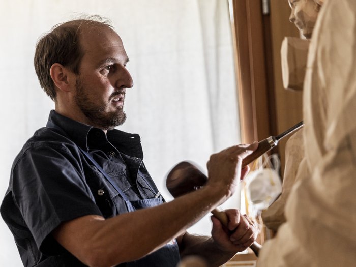 L’artigianato artistico di lvh.apa compie 75 anni Uomo scolpisce una scultura di legno con uno scalpello in un laboratorio