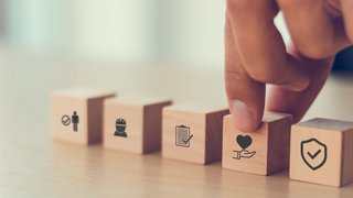 Webinare Hand tippt auf Holzblock mit Herz-Symbol neben anderen Symbolblöcken