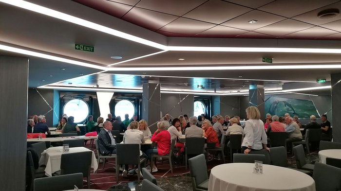 Artigiani anziani in crociera Gruppo di persone anziane sedute in una sala da pranzo moderna con finestre rotonde