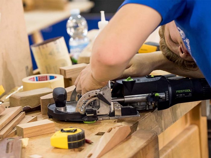 Wer darf nun effektiv arbeiten? Person arbeitet mit Festool Domino Werkzeug auf Holzbearbeitungstisch