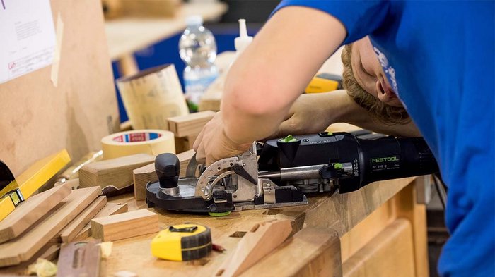 Wer darf nun effektiv arbeiten? Person arbeitet mit Festool Domino Werkzeug auf Holzbearbeitungstisch