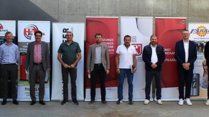 Ausbildung hoch drei Elft Männer stehen vor Werbebannern in einer Industriehalle