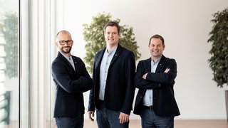 lvh-Präsidium, ©Florian Andergassen Drei Männer in blauen Jacken stehen in modernem Büro vor Pflanzen