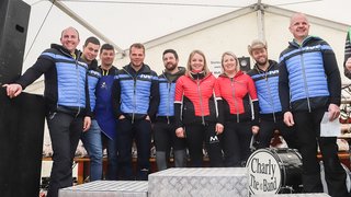 News Gruppe von zehn Personen in bunten Jacken bei Veranstaltung im Zelt