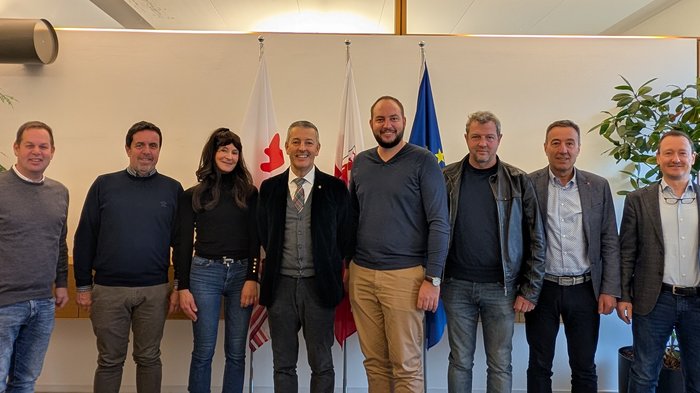 Tiefbauunternehmer/innen im lvh treffen Landesrat Peter Brunner Acht Personen stehen vor drei Fahnen in einem Büro