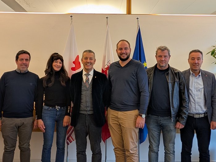 Tiefbauunternehmer/innen im lvh treffen Landesrat Peter Brunner Acht Personen stehen vor drei Fahnen in einem Büro