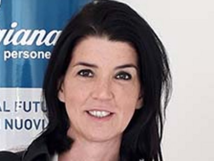 „Es wird Zeit, dass wir wieder aufsperren dürfen!“ Porträt einer lächelnden Frau vor einem blauen Artigiana-Banner