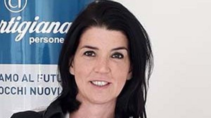 „Es wird Zeit, dass wir wieder aufsperren dürfen!“ Porträt einer lächelnden Frau vor einem blauen Artigiana-Banner