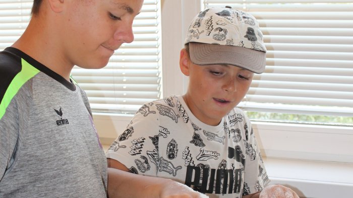 Backspaß und Kreativität – KidsAcademy backt in Kaltern Zwei Jungen verrühren Mehl in Schüsseln am Küchentisch bei Tageslicht