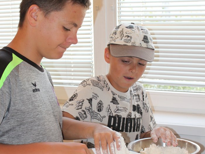 Backspaß und Kreativität – KidsAcademy backt in Kaltern Zwei Jungen verrühren Mehl in Schüsseln am Küchentisch bei Tageslicht