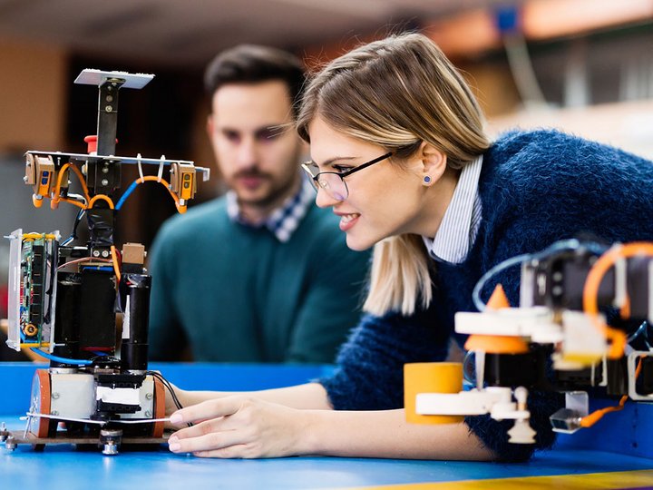 Formazione professionale Donna e uomo che lavorano insieme a un robot in laboratorio