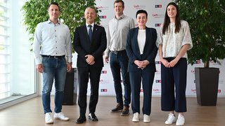 Abitare deve essere accessibile! Cinque persone in piedi davanti a muro con loghi LVH APA, sorridenti e formali