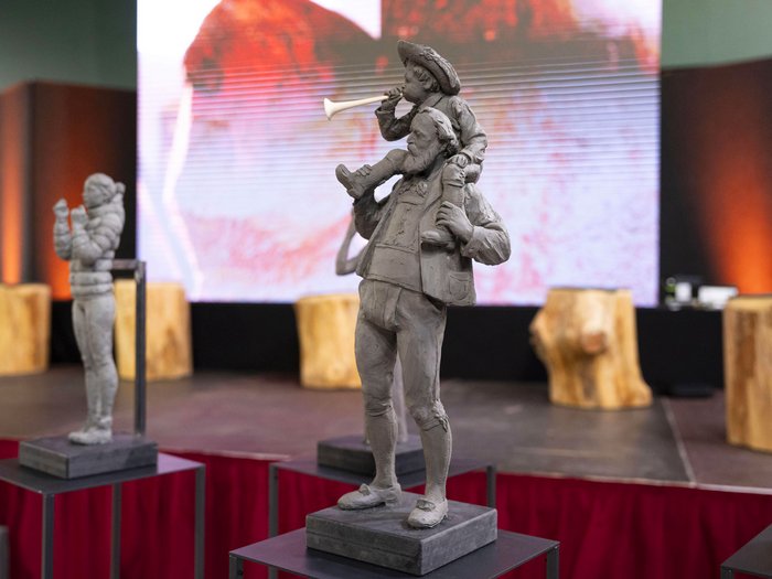 La 31^ Fiera d’Arte UNIKA apre le porte a Ortisei Statua di un uomo con un bambino sulle spalle che suona una trombetta