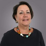 Das lvh-Team Porträt einer Frau mit buntem Perlenhalsband vor grauem Hintergrund