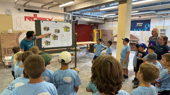 Kids-Academy 2024: Eine lehrreiche Erfahrung im Vinschgau Kinder in blauen T-Shirts erhalten Bauanleitung von Lehrer in Werkstatt