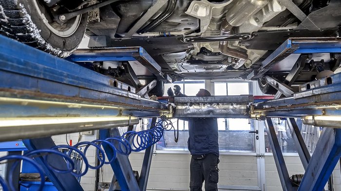KFZ-Sektor: Kunden dürfen selbst in die nächste Werkstatt fahren Mechaniker inspiziert Fahrzeugunterseite in Autowerkstatt auf Hebebühne