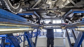 News Mechaniker inspiziert Fahrzeugunterseite in Autowerkstatt auf Hebebühne