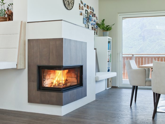 14. Oktober: Tag des Kachelofens Moderne Ecke mit brennendem Kamin, Wanduhren und Essbereich mit Aussicht