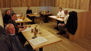 News Gruppe von acht Personen bei Besprechung an Holztischen in gemütlichem Raum