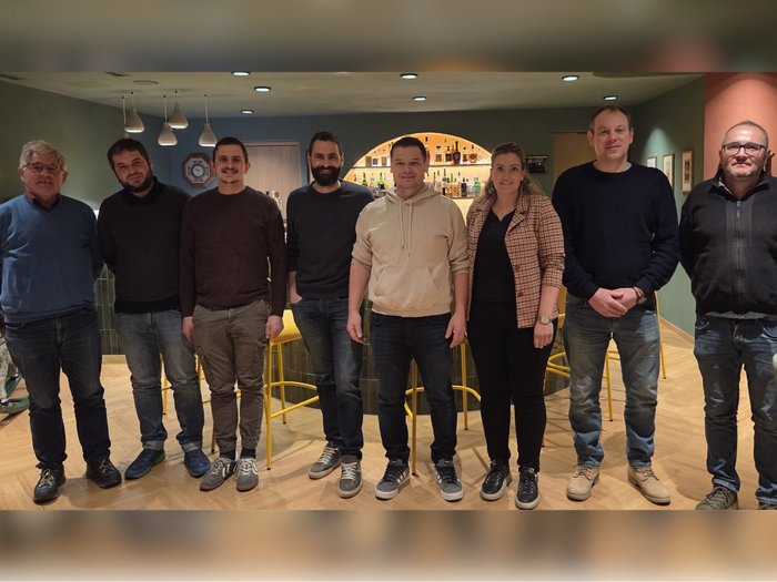 Handwerk stärkt Gemeinschaft – und macht Zukunft greifbar Acht Personen stehen nebeneinander in einem Zimmer mit Bar im Hintergrund