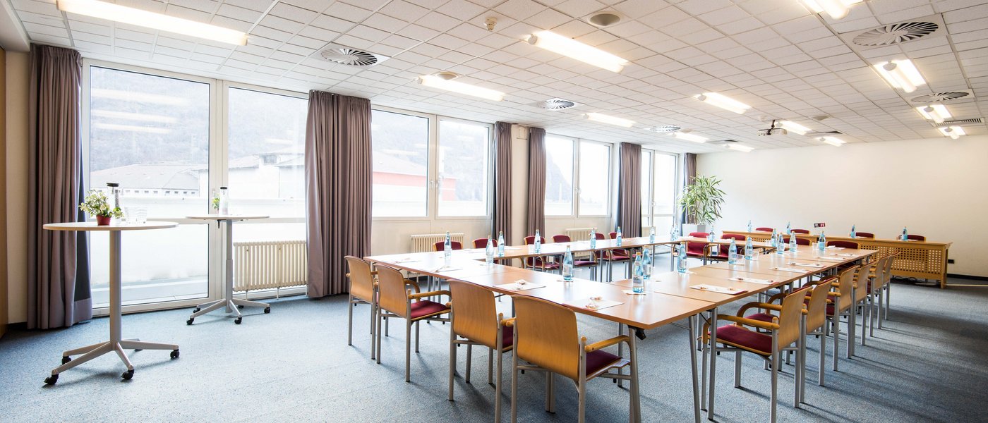 Vermietung Seminarräume Heller Konferenzraum mit Tischen, Stühlen und Wasserflaschen vorbereitet für Meeting