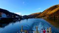 Auf Reisen: Althandwerker auf Flusskreuzfahrt Blick von einem Boot auf einen Fluss mit Hügeln und Sitzbereichen auf dem Deck