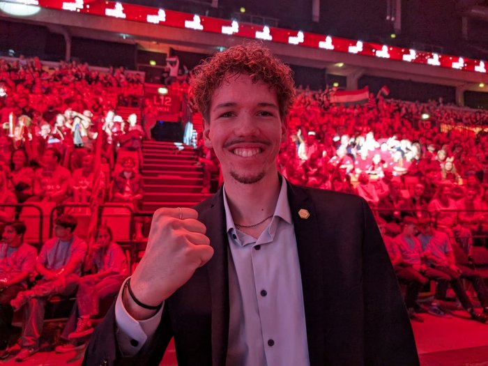 Titolo europeo per i giovani artigiani altoatesini: lvh si congratula per i successi straordinari agli EuroSkills 2025 Giovane in giacca davanti a folla festante con luce rossa