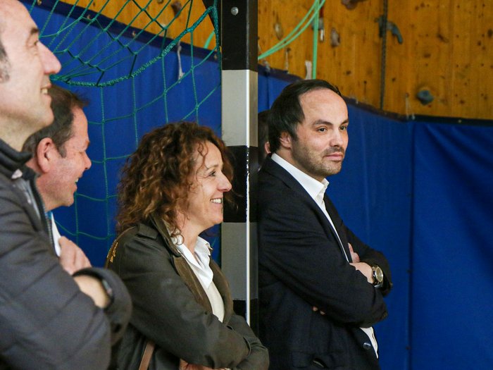 Kreative Spielideen: Preisverleihung für "Clever gebaut" Vier Personen in einer Halle beobachten aufmerksam ein Ereignis mit verschränkten Armen