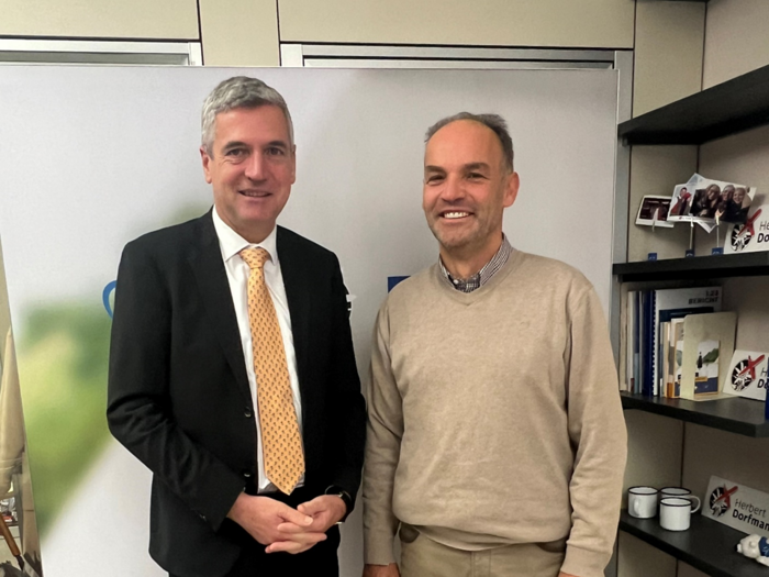 Le sfide del trasporto merci Due uomini in ufficio, uno in abito e cravatta, l'altro in maglione, sorridenti