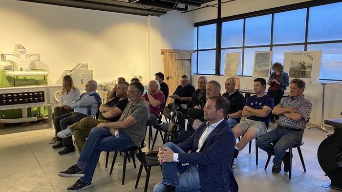 Handwerk gestaltet mit! Gruppe von Personen sitzt auf Stühlen und hört in einem hellen Raum aufmerksam zu