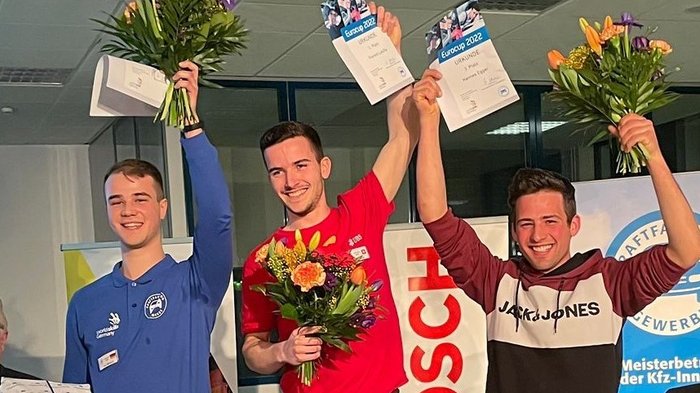 Kfz-EuroCup: Südtiroler gewinnt Bronze Drei junge Männer halten Urkunden und Blumensträuße bei einer Siegerehrung hoch