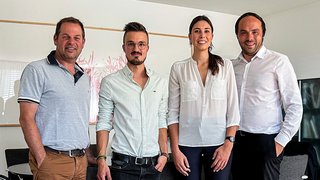 News Vier Personen in Büro mit legerer und formeller Kleidung posieren für Gruppenfoto