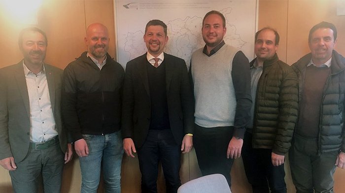 Tiefbauunternehmer bei Landesrat Alfreider Sechs Männer stehen lächelnd vor einer Wand mit einer Landkarte