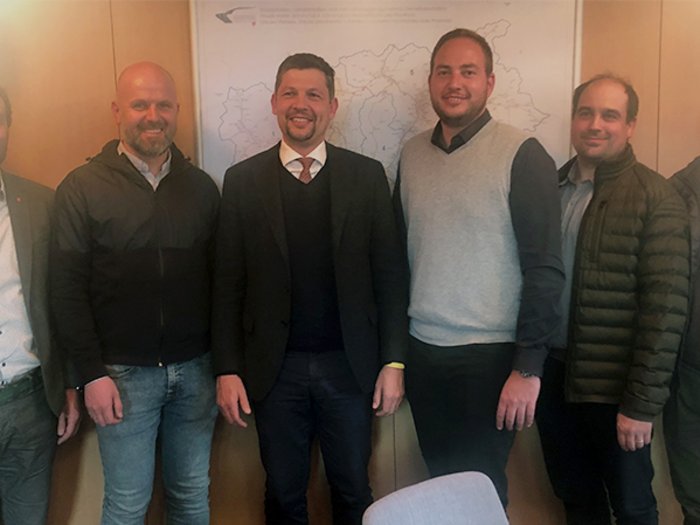 Tiefbauunternehmer bei Landesrat Alfreider Sechs Männer stehen lächelnd vor einer Wand mit einer Landkarte