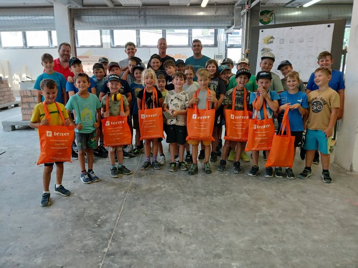 Handwerk zum Anfassen: KidsAcademy begeistert Kinder in Schlanders Gruppenfoto von Kindern mit orangen Terzer-Taschen in einer Halle