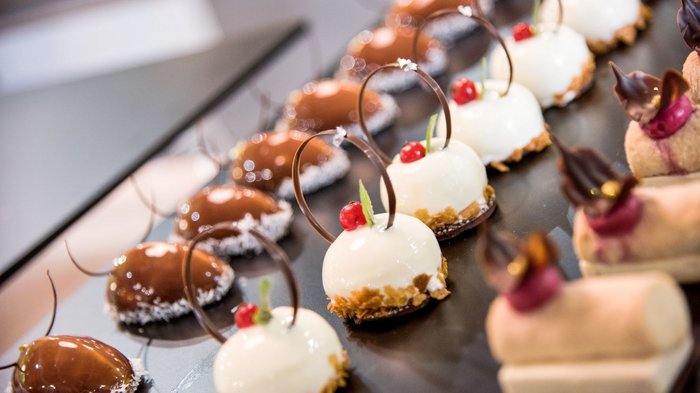 Der Tag der Herzen Verschiedene kunstvoll dekorierte kleine Kuchen auf Tablett angerichtet