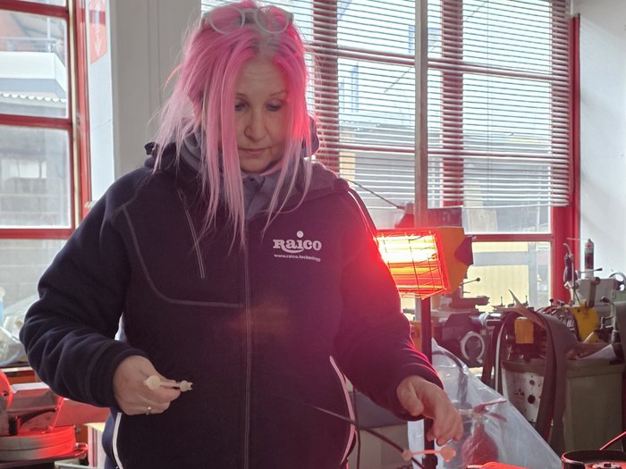 Handwerk ist weiblich – und selbstbewusst Frau mit pinken Haaren in Werkstatt hält kleine Teile in der Hand